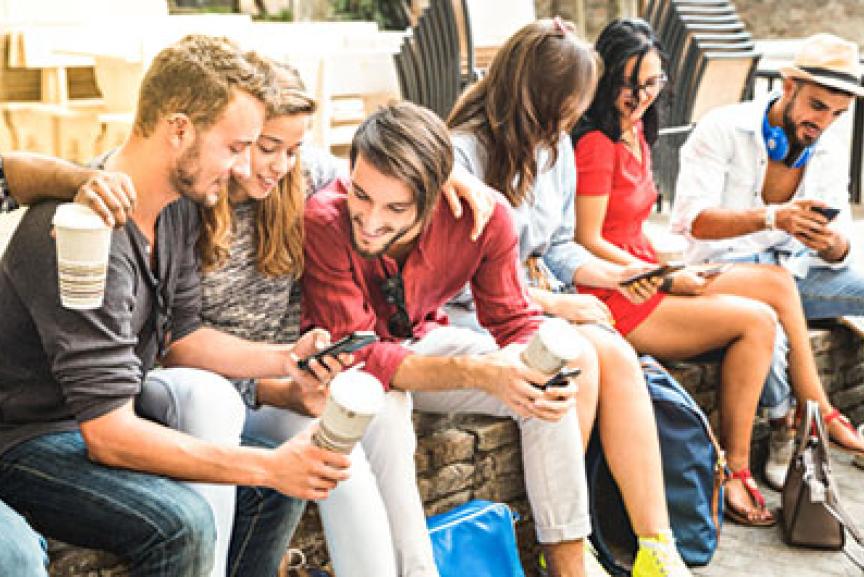 Junge Frauen und Männer auf Holzstapel mit Smartphone