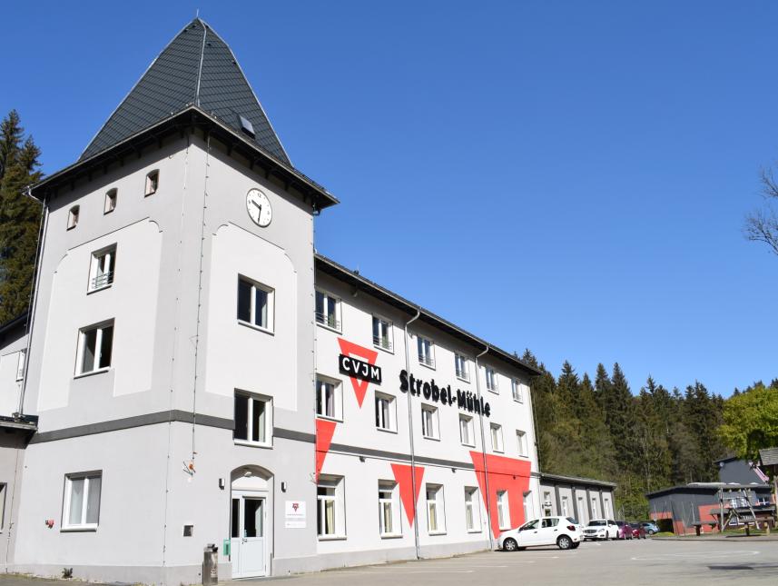 Ansicht Gruppenhaus, gestrichen in verschiedenen Grautönen und mit dem CVJM Strobel-Mühle Schriftzug