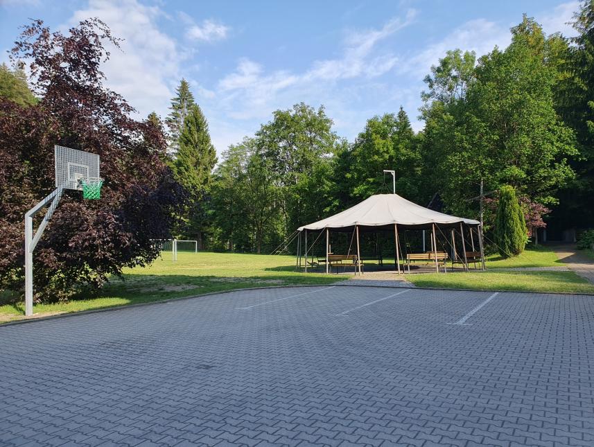 Hof mit Blick zum Streetballkorb, Spielwiese mit Fußballtoren und der Lagerfeuerstelle mit Jurtendach