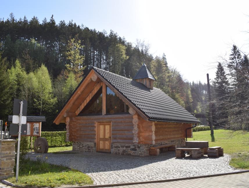 Blockhauskapelle mit Glockentürmchen, Sitzecke und Schaukasten