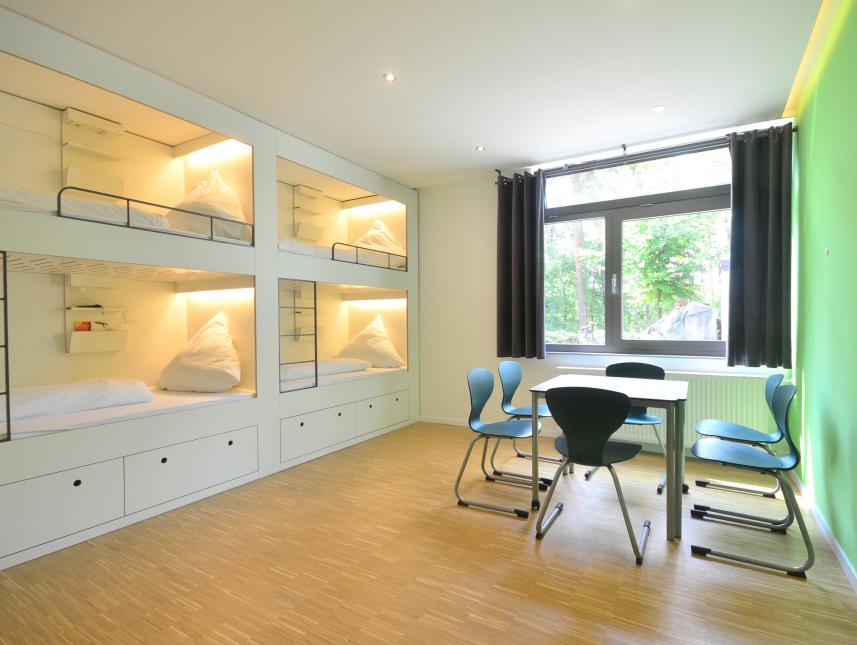 Im Grünen Haus findest du moderne Sechsbettzimmer mit gemütlichen Schlafkojen und ein Begleiterzimmer mit separatem Bad. 
