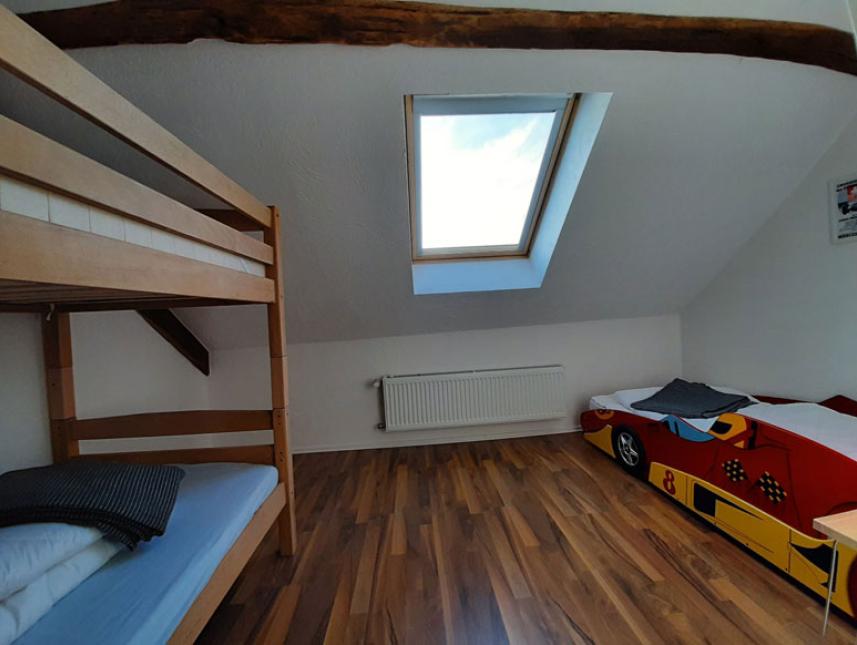 Schlafzimmer mit Etagenbett und Bett in Rennauto-Optik