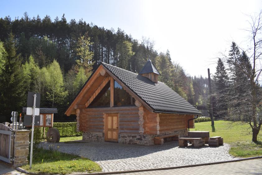 Blockhauskapelle mit Glockentürmchen, Sitzecke und Schaukasten