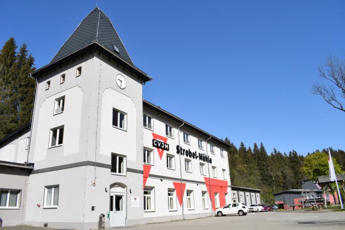 Ansicht Gruppenhaus, gestrichen in verschiedenen Grautönen und mit dem CVJM Strobel-Mühle Schriftzug