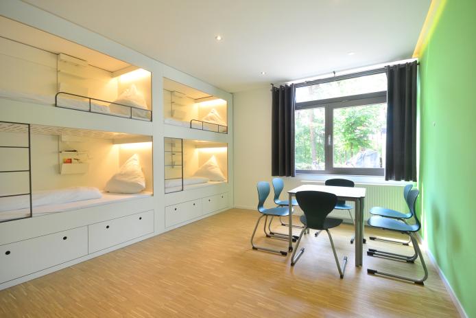 Im Grünen Haus findest du moderne Sechsbettzimmer mit gemütlichen Schlafkojen und ein Begleiterzimmer mit separatem Bad. 